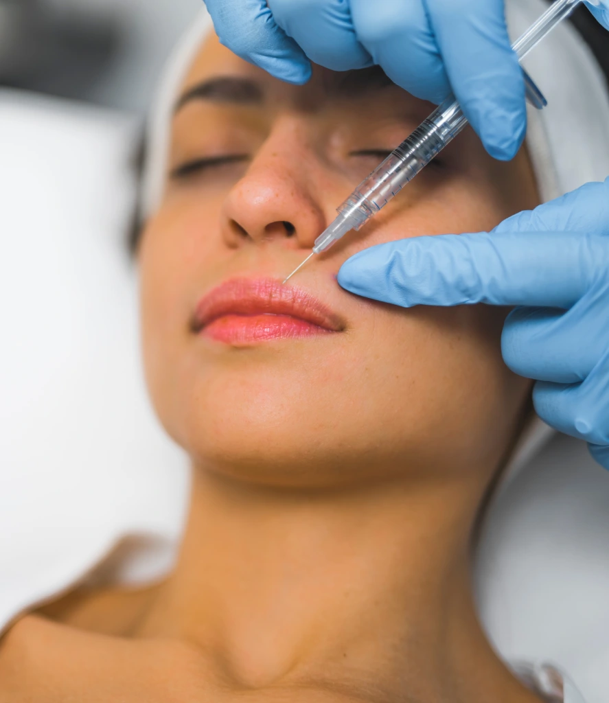 Medical professional injects dermal filler into a woman's cheek using a fine needle during a Dermal Fillers Treatment in Centennial CO at Refine Med Spa. The procedure enhances facial volume and smooths fine lines for a youthful appearance.