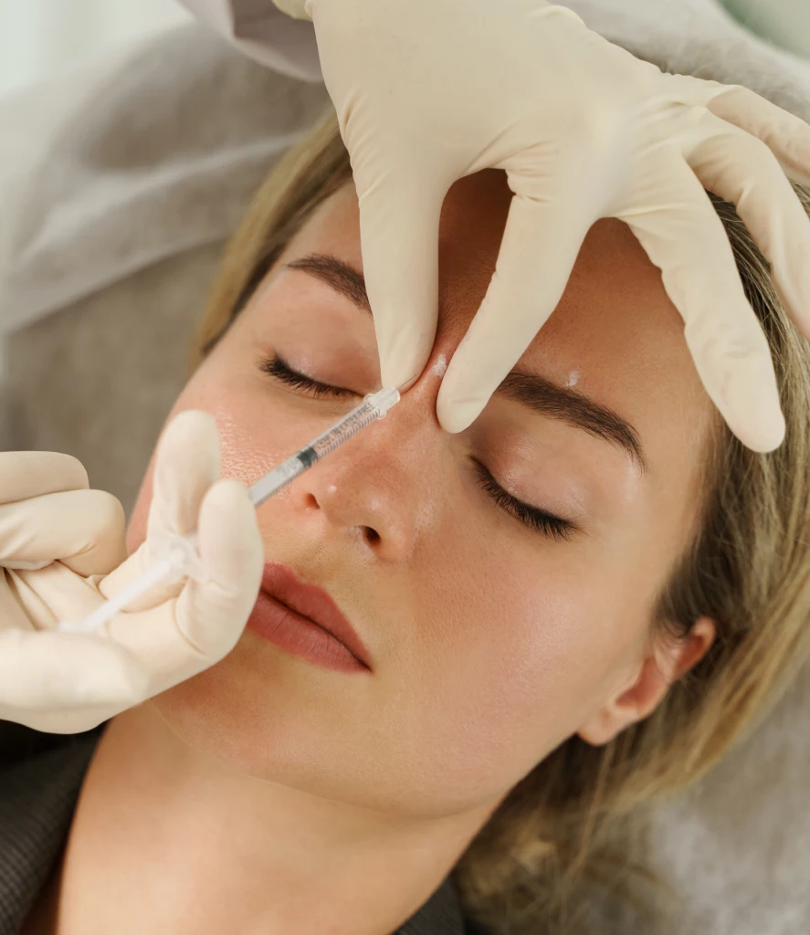 A medical professional injects dermal filler into a woman's Face using a fine needle during a Dermal Fillers Treatment in Centennial, CO at Refine Med Spa. The procedure enhances facial volume and smooths fine lines for a youthful appearance.