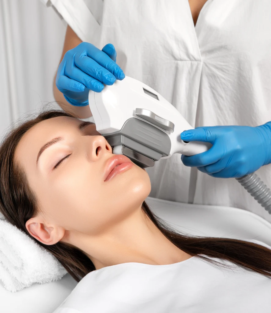 Close-up of a clinician performing IPL PhotoFacial Treatment on a woman's face using a handheld light-based device. The procedure at Refine Med Spa in Centennial CO targets sun damage, redness, and uneven skin tone for a clearer complexion.