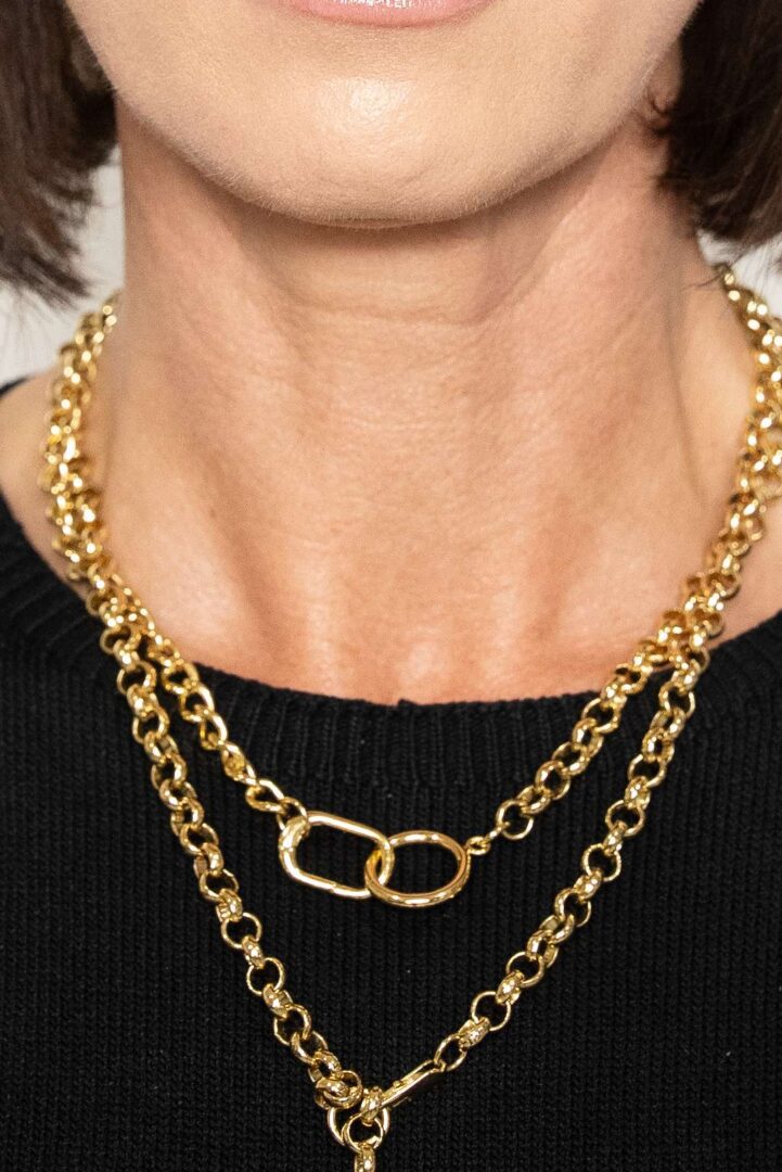 Layered gold chain necklaces on black sweater