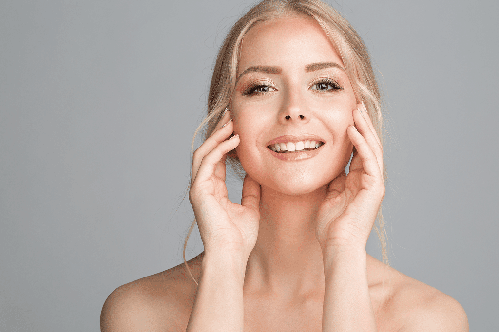 Smiling blonde woman gently touching her face