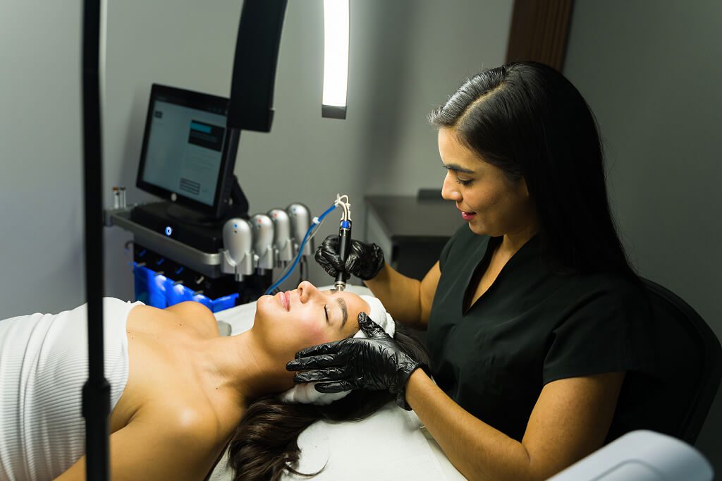 Esthetician performing microneedling facial on client