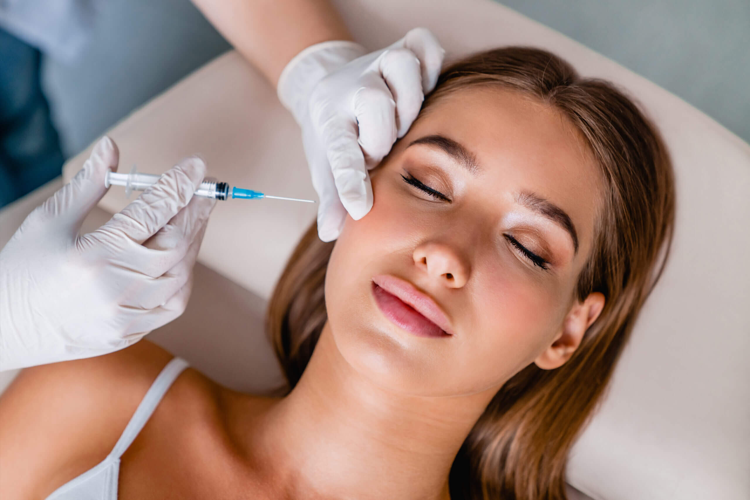 Woman receiving cosmetic filler injection near eye