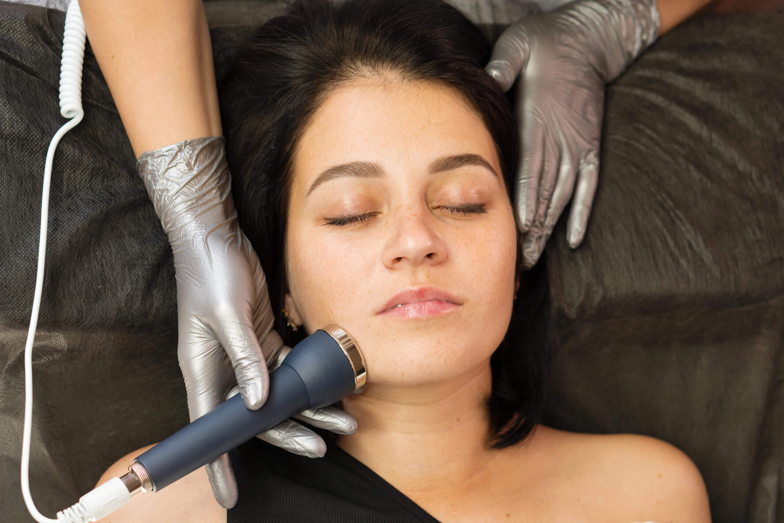 Woman receiving skincare facial with handheld device